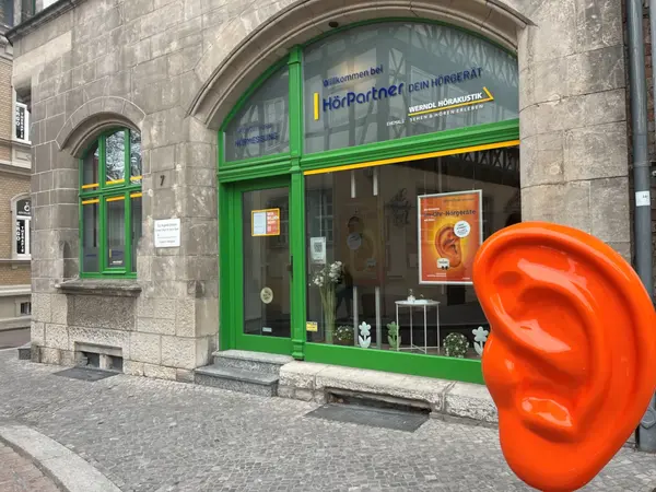 Schaufenster eines Hörakustikers mit Hörgeräte-Werbung und großer Ohrfigur