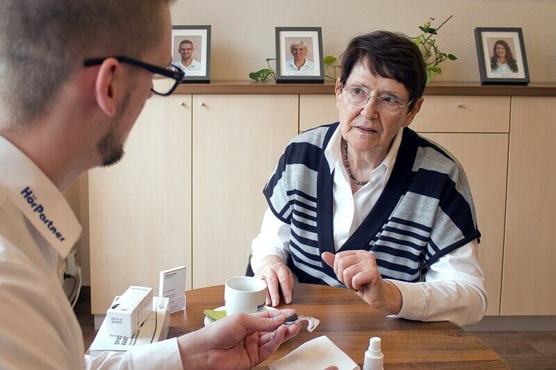 Ärztin berät Patienten in Praxis, Medikamentenpackungen auf dem Tisch.